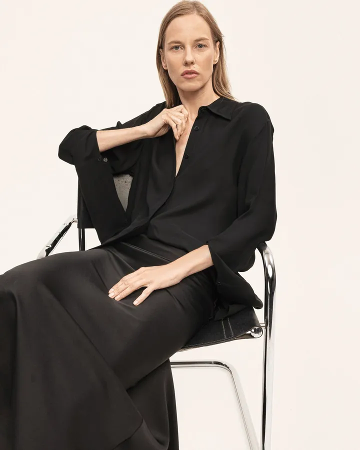 Fluid black silk shirt, model seated
